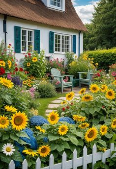 a garden with sunflowers and other flowers in front of a house