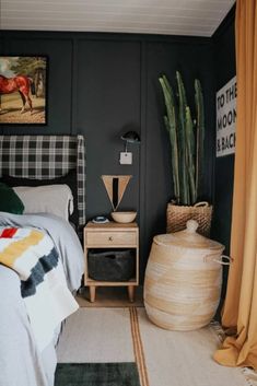 a bed room with a neatly made bed next to a painting on the wall and a potted plant