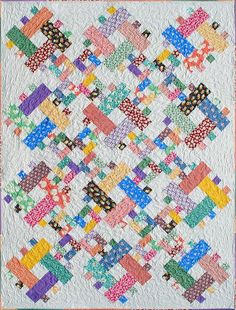 a quilt made with colorful squares and dots on the front, along with a white background