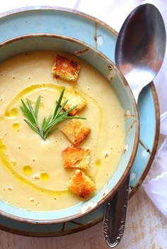 a blue bowl filled with soup and croutons