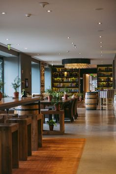 an empty restaurant with wooden tables and planters on the wall, in front of large windows