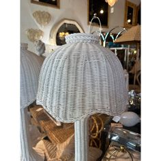 two white wicker lamps sitting on top of a table next to other items in a store