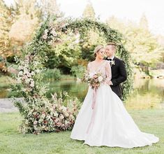 a bride and groom standing in front of a floral arch