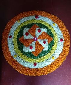 a cake decorated with orange, white and green flowers on top of a red table