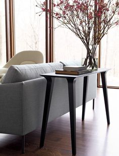 a living room with a couch, table and vase filled with flowers on the coffee table