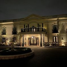 a large white house lit up at night with christmas lights on the windows and balconies