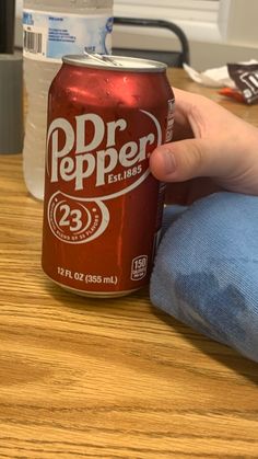 a person is holding a can of dr pepper