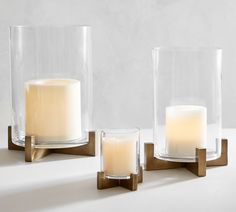 three glass vases with candles in them on a table