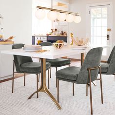 a dining room table with four chairs and a bowl of fruit on the table in front of it