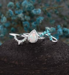 an opal and diamond ring sitting on top of a rock