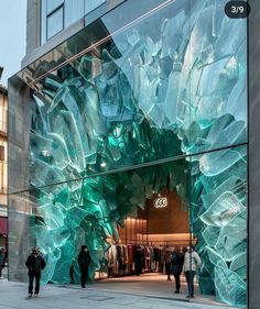 people are walking in front of a store with large glass sculptures on the side of it