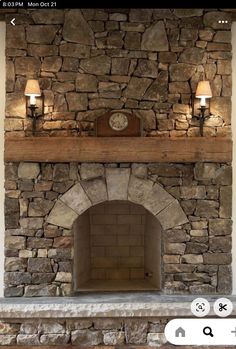 a stone fireplace with two lamps on each side and a clock above the fire place