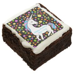 a square brownie with white frosting and a unicorn on the top, surrounded by flowers