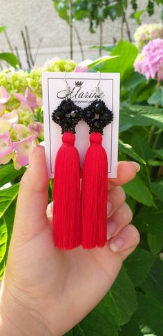 a pair of red tasselled earrings with black beads