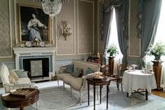 a living room filled with furniture and a chandelier hanging from the ceiling over a fire place