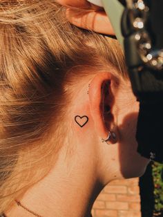 a woman with a small heart tattoo behind her ear