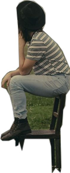 a man sitting on top of a wooden bench wearing a black hat and blue jeans