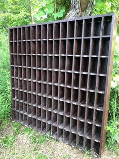 an old wooden crate sitting in the grass next to a tree with lots of shelves on it