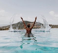 a person splashing water in the ocean with their arms up and hands out to the side