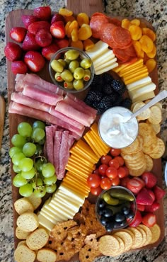 an assortment of cheeses, crackers, grapes and meats on a platter