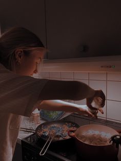 a woman is cooking in the kitchen with her hand on the stove top burner