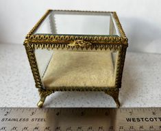 a small glass box sitting on top of a ruler