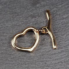 Size: Eyelet (heart): 17.5 x 4.7 x 2.2 mm Rod: 25.1 x 1.7 mm Thread eyelet: 3 mm Material: brass, 24 carat gold plated Quantity: 1 set Item number: 11096 This toggle clasp in a minimalist heart design is ideal for bracelets and necklaces. The clasp is made of high-quality brass and is 24-carat gold-plated, giving it a luxurious look. The heart loop measures 17.5 x 4.7 x 2.2 mm, the bar has a length of 25.1 x 1.7 mm, and the threading loop has a diameter of 3 mm. The toggle clasp is not only func Gold Metal Toggle Necklace With Heart Charm, Gold Heart Pendant Toggle Necklace, Heart-shaped Jewelry With Clasp For Gifts, Gold Toggle Necklace With Heart Pendant, Heart-shaped Jewelry Gift With Clasp, Gold Heart Toggle Necklace With Toggle Clasp, Gold Heart Pendant Toggle Necklace As Gift, Gold Heart-shaped Toggle Necklace, Elegant Heart Shaped Toggle Necklace