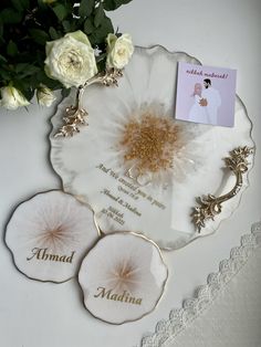 three plates with flowers and cards on them sitting on a lace tablecloth next to a bouquet of white roses