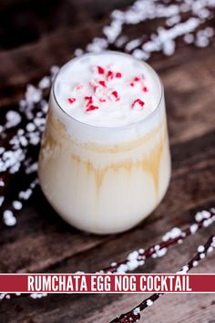 a glass filled with milk and candy canes on top of a wooden table covered in snow