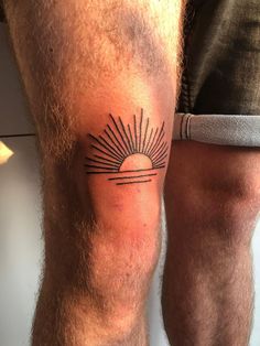 a man with a tattoo on his leg that has the sun in it's center