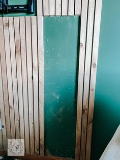 a green door is in the corner of a room with wood paneling on it