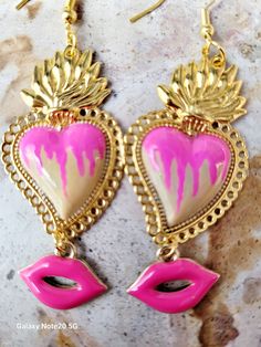 Beautiful and modern hand-painted sacred heart earrings, in natural beige and pink colors, adorned with pink lips, are protected with several layers of high-quality jewelry varnish, improving the quality and durability of the earrings. These hand-painted sacred heart earrings are unique and very beautiful, the ideal gift because they combine with any outfit both day and night, they will enhance the beauty and you will surely attract attention due to the unique and artisanal design, the Ideal gift for the Day of Mothers, weddings and holidays. Features/ Product info Note: The earrings in stock have some differences because they are hand painted. -The Main Material: Zinc Alloy (Gold) -Color: Natural beige and pink -Small: 1 in  (Please see the photos, this design comes in two sizes.) - Earri Pink Artsy Jewelry For Festivals, Artsy Pink Jewelry For Festivals, Hand Painted Gold Earrings For Festival, Gold Hand Painted Earrings For Festivals, Artsy Pink Earrings For Festivals, Artsy Pink Festival Jewelry, Artsy Hand Painted Pink Jewelry, Bohemian Multicolor Heart Earrings For Valentine's Day, Unique Hand Painted Heart Earrings