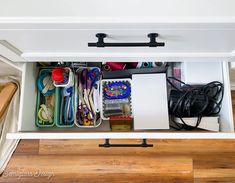 an organized drawer with scissors and other crafting supplies in it on top of a wooden floor