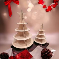 three wooden christmas trees sitting on top of a table next to a pine cone and red ribbon