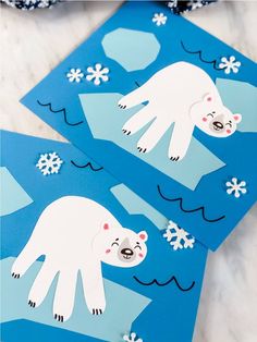 two polar bears cut out from paper with snowflakes on the ground behind them