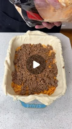 a person holding a bag of food in front of a bowl with some kind of topping on it