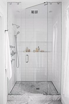 a white tiled bathroom with shower and sink