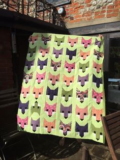 a quilt is hanging on a clothes line in front of a brick wall and chair