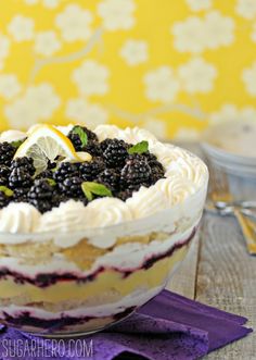 a cake with white frosting and blackberries on top is sitting on a table