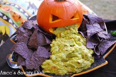 a plate with chips, guacamole and a jack - o'- lantern pumpkin