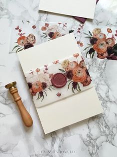 two cards with flowers on them next to a wax stamper and a wooden mallet