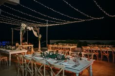 an outdoor dining area with string lights and wooden tables set up for a wedding reception