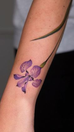 a woman's arm with a purple flower tattoo on the left side of her arm