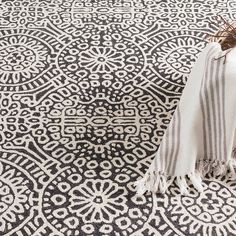 a black and white area rug with fringes on the floor next to a chair