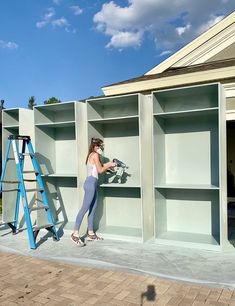 a woman is standing in front of some shelving units and using a ladder to move the shelves