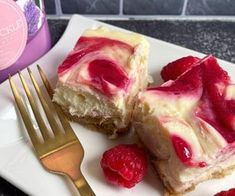 two pieces of cake with raspberry toppings on a plate next to a fork