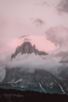 the mountains are covered in clouds and pink hues