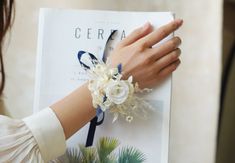 a woman wearing a bracelet with flowers on it and holding a book in her hand