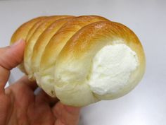 a hand holding a piece of bread with cream on it