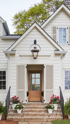 a white house with steps leading up to the front door and flowers in planters